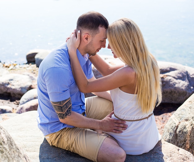 Portrait d'heureux jeune beau couple assis sur une plage rocheuse