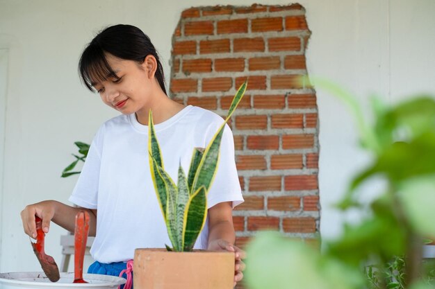 Portrait heureux jeune fille planter un arbre en pot à la maison