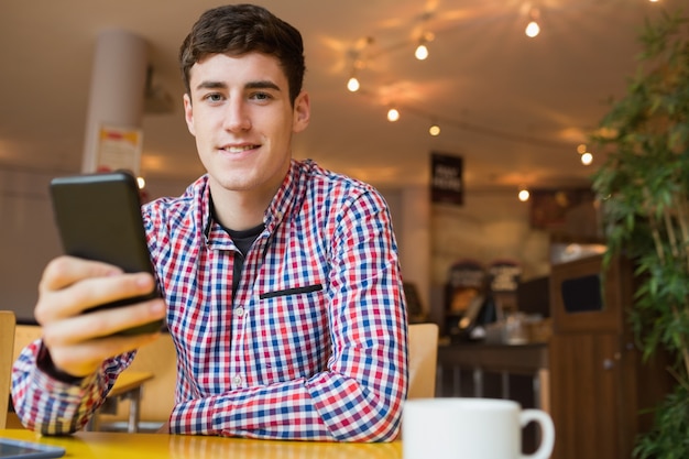 Portrait de l&#39;heureux jeune homme à l&#39;aide de téléphone portable