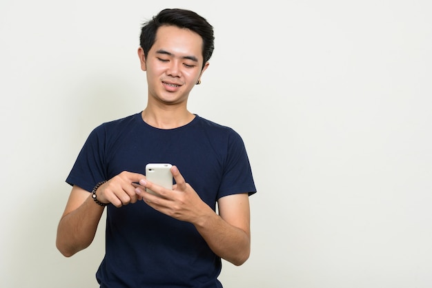 Portrait de l'heureux jeune homme asiatique à l'aide de téléphone