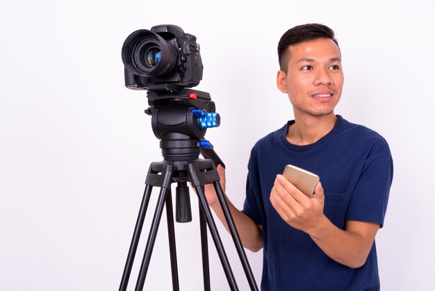 Portrait de l'heureux jeune homme asiatique avec appareil photo à l'aide de téléphone