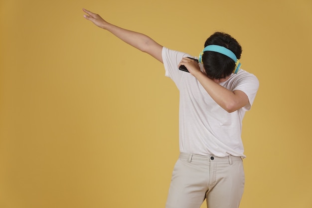 Portrait d'heureux joyeux joyeux jeune homme asiatique portant des écouteurs, écouter de la musique sur smartphone et danser isolé