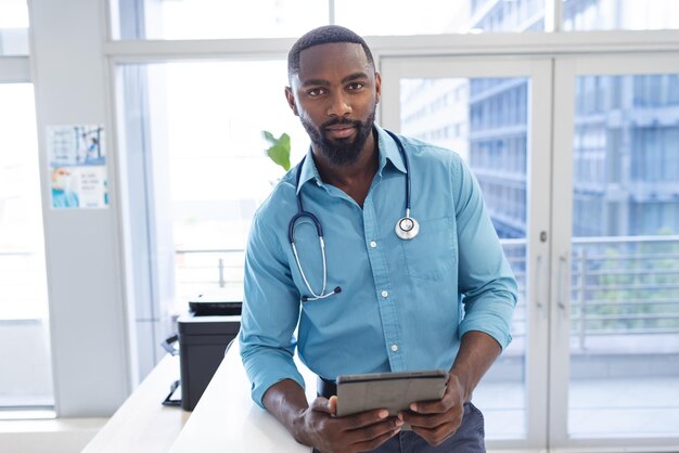 Photo portrait d'un heureux médecin afro-américain tenant une tablette à la réception d'un hôpital