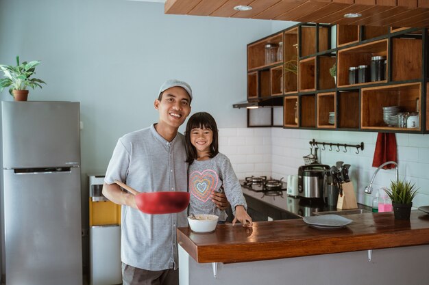 Portrait de l'heureux père et fille asiatique cuisiner ensemble dans une cuisine moderne