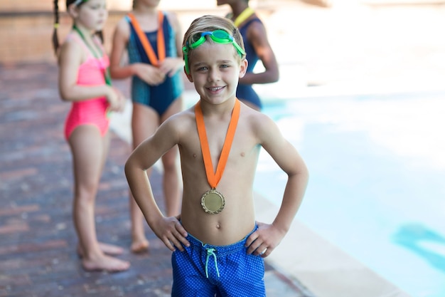 Portrait de l'heureux petit garçon portant la médaille au bord de la piscine