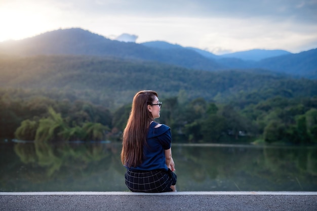 Portrait heureux et relaxant d'une femme asiatique portant une robe bleu foncé assise sur l'herbe verte