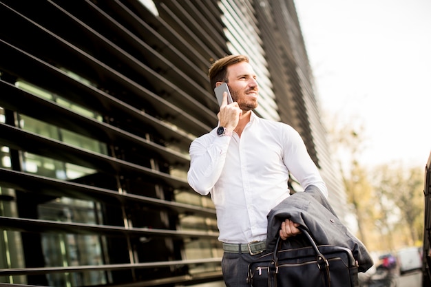 Portrait de heureux souriant homme d&#39;affaires urbain à l&#39;aide de téléphone intelligent à l&#39;extérieur