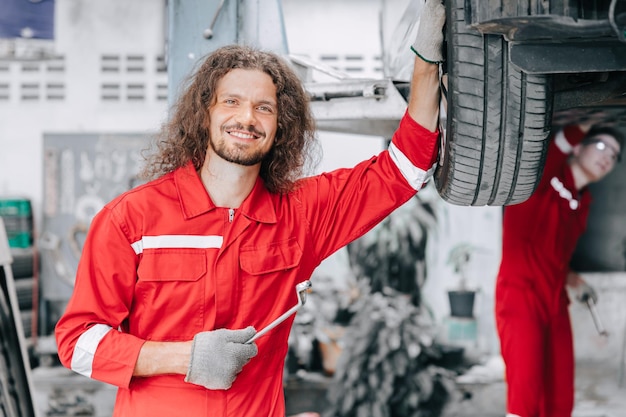 Portrait heureux travailleur du personnel de garage mécanicien profiter de remplacer les pneus de service de voiture dans l'atelier automobile de garage