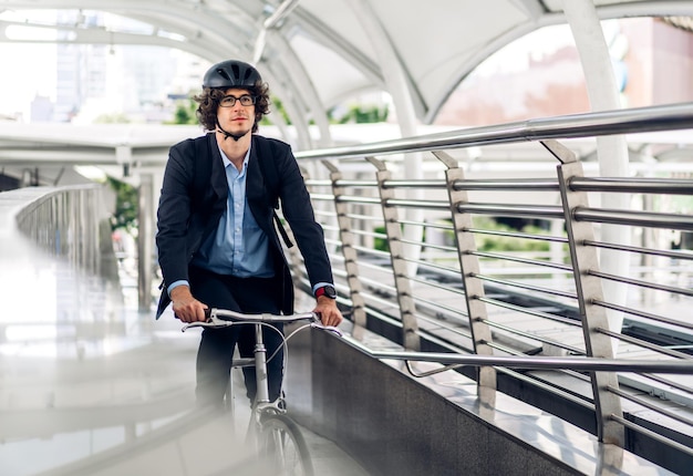 Portrait de hipster bel homme d'affaires en costume avec sac à dos avec impatience tout en faisant la navette à vélo dans la rue ville aller au travailconcept de vélo de transport de voyage d'affaires