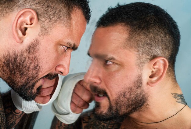 Portrait de hipster homme en colère agressif look brutal mec mécontent regarde le miroir frustration