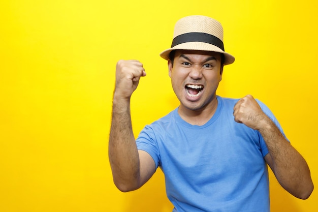 Portrait de Hipster jeune homme jeune homme heureux tenue décontractée t-shirt rayé bleu et porter un chapeau Geste émotion étendre les bras timide modeste sur les portraits en studio définir la couleur fond jaune