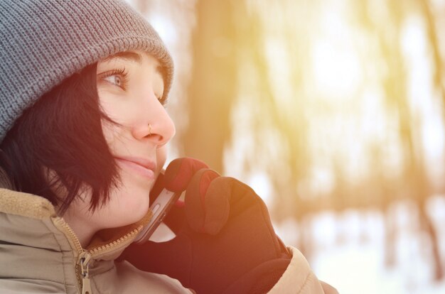 Photo portrait d'hiver de jeune fille avec smartphone