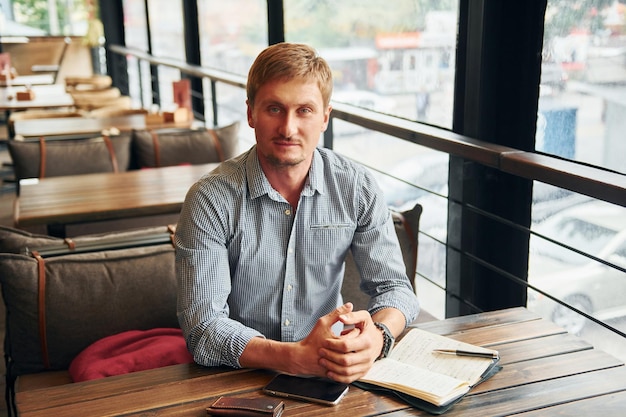 Portrait d'un homme adulte assis à l'intérieur près de la table du café