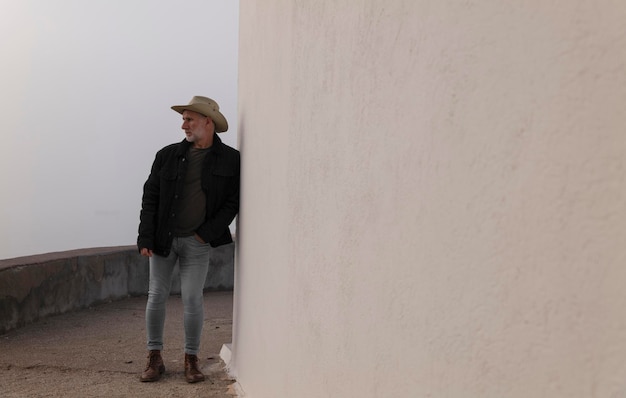 Portrait d'un homme adulte avec un chapeau de cow-boy et des jeans contre le mur