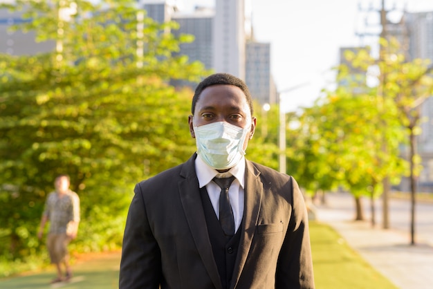 Portrait d'homme d'affaires africain avec masque dans le parc de la ville
