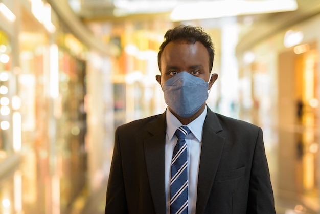 Portrait d'un homme d'affaires africain portant un costume et un masque facial pendant la distanciation sociale