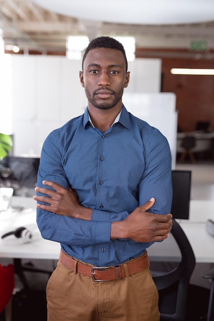 Portrait d'un homme d'affaires afro-américain debout au bureau, les bras croisés regardant la caméra. travailler en affaires dans un bureau moderne.