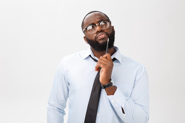 Portrait d'un homme d'affaires afro-américain pensif dans un costume gris pensant avec un stylo sur son visage