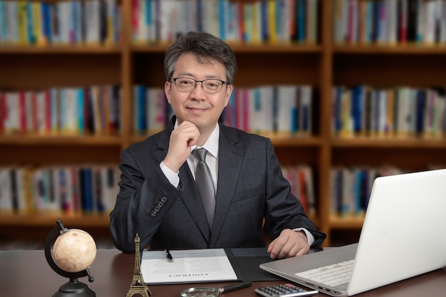 Portrait d'un homme d'affaires asiatique d'âge moyen assis à un bureau.