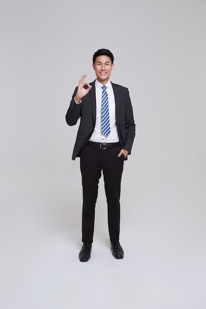 Portrait d'un homme d'affaires asiatique en costume gris confiant montre ok geste approuve le plan