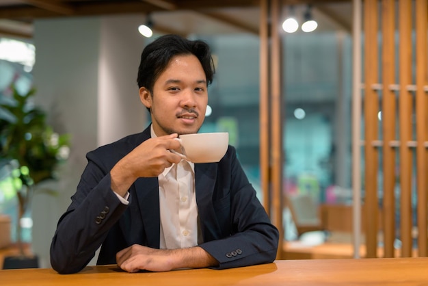 Portrait d'homme d'affaires asiatique dans un café buvant du café