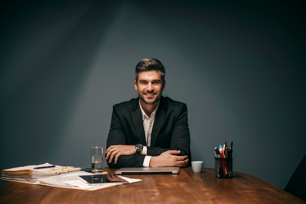 Portrait d'un homme d'affaires assis au bureau et souriant à la caméra