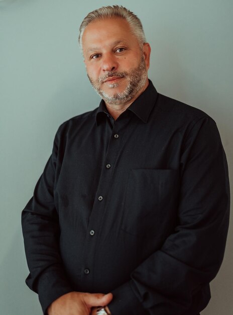 Photo portrait d'un homme d'affaires aux cheveux gris avec une barbe portant un costume sur fond gris