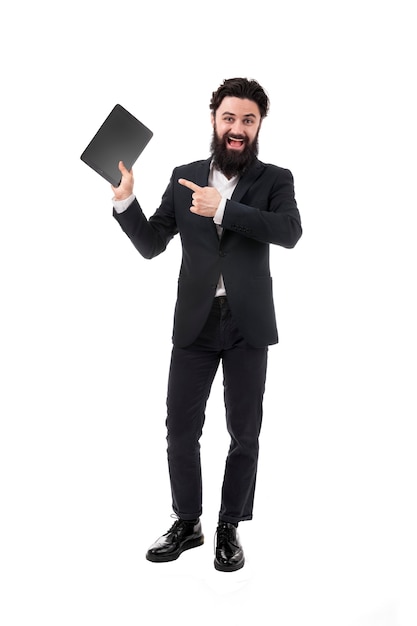 Portrait d'homme d'affaires barbu avec tablette à la main, homme pointant sur l'écran de la tablette vierge, isolé sur un mur blanc