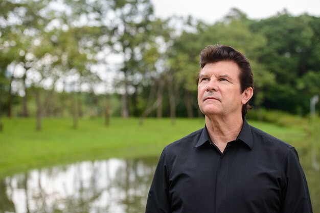 Portrait d'homme d'affaires beau mature se détendre dans le parc en plein air