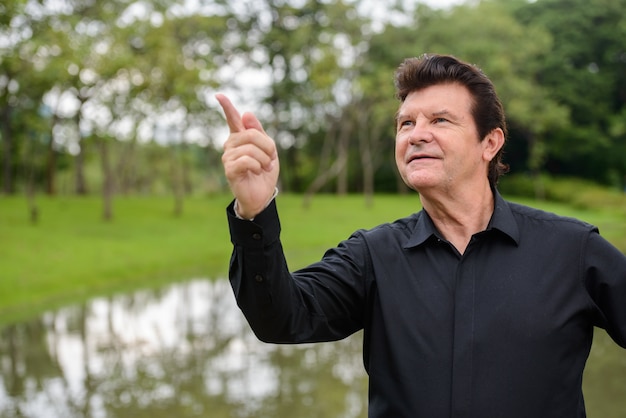 Portrait d'homme d'affaires beau mature se détendre dans le parc en plein air