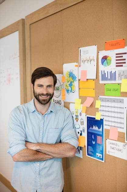 Portrait d'homme d'affaires confiant debout par soft board au bureau