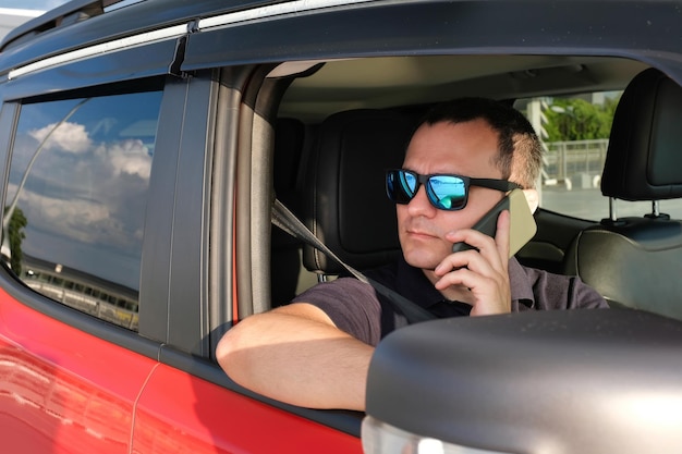 Portrait d'un homme d'affaires dans une voiture parlant au téléphone