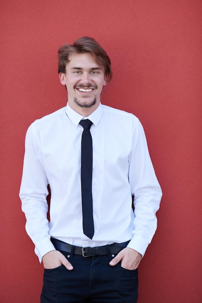 portrait d'homme d'affaires de démarrage dans une chemise blanche avec une cravate noire debout devant un mur rose à l'extérieur