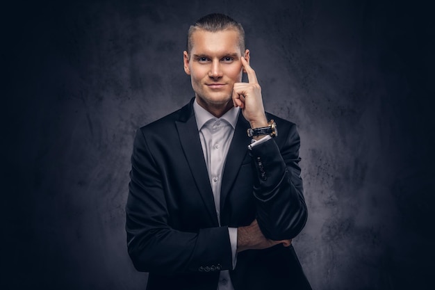 Un portrait d'un homme d'affaires élégant et souriant sur un fond sombre.