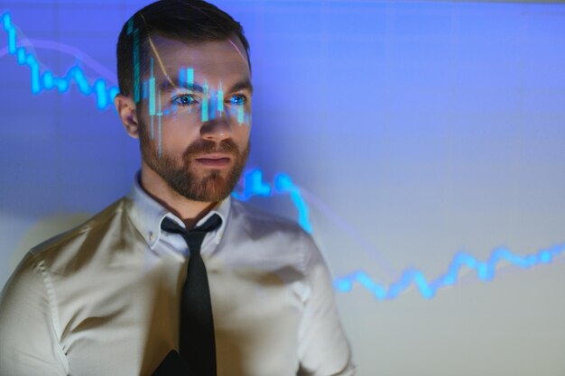 Portrait d'un homme d'affaires européen concerné pensant dans un bureau flou avec une double exposition d'un graphique financier en baisse Concept de crise et de marché boursier