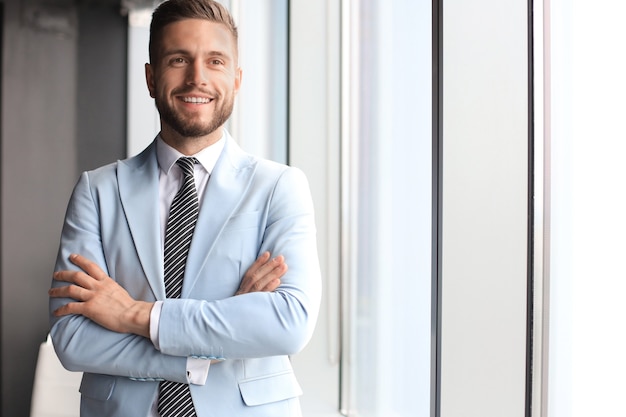 Portrait d'homme d'affaires heureux avec les bras croisés debout au bureau.