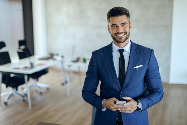 Portrait d'un homme d'affaires heureux avec un téléphone intelligent au bureau