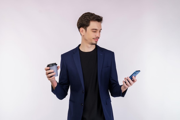 Portrait d'un homme d'affaires heureux utilisant un smartphone et tenant un café chaud sur blanc