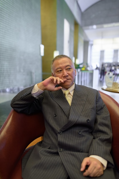 Portrait d'homme d'affaires japonais mature se détendre à l'intérieur du café