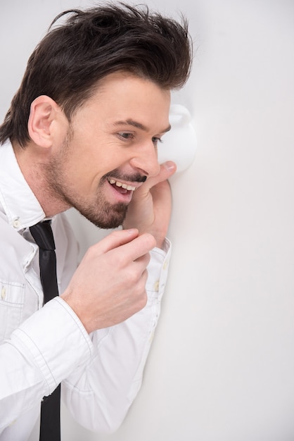 Portrait d'un homme d'affaires jeune utilisant un verre comme téléphone.