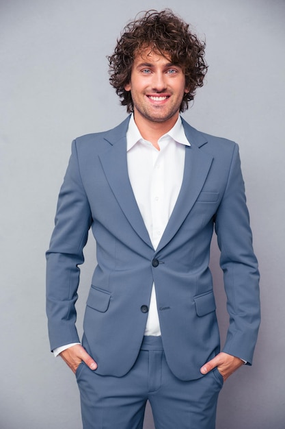 Portrait d'un homme d'affaires joyeux debout sur un mur gris