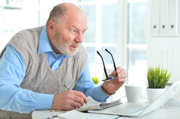 Portrait d'un homme d'affaires mature émotionnel travaillant avec un ordinateur portable au bureau