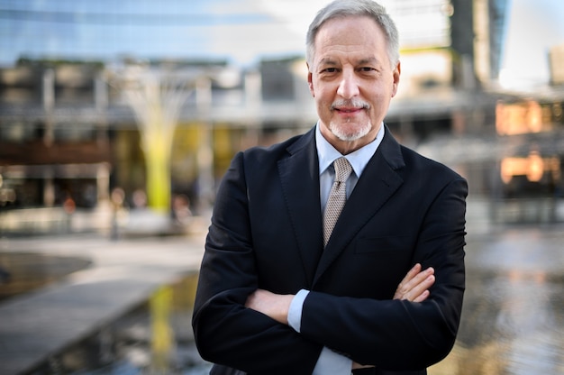 Portrait d'homme d'affaires mature en plein air avec les bras croisés