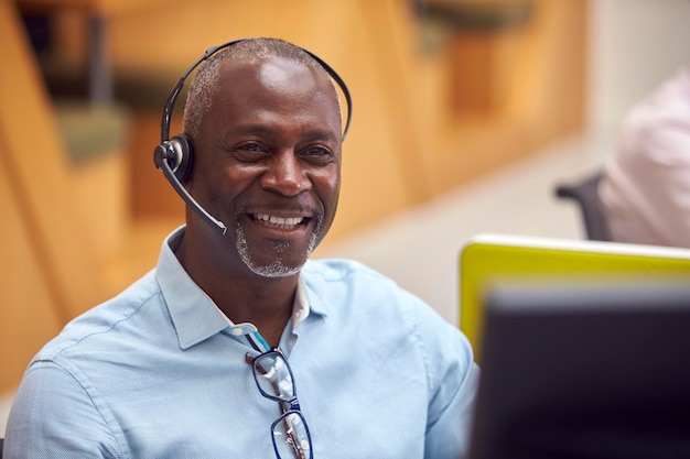 Portrait d'homme d'affaires mature portant un casque téléphonique parlant à l'appelant dans le centre de services client