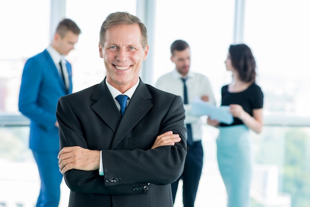 Portrait d'un homme d'affaires mature souriant avec les bras croisés