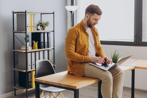 Photo portrait d'un homme d'affaires moderne en chemise jaune travaillant sur un ordinateur portable dans le bureau