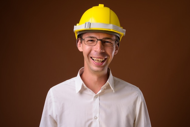 Portrait d'homme d'affaires portant un casque contre un mur marron