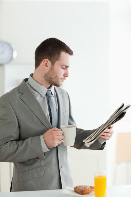 Portrait d&#39;un homme d&#39;affaires prenant son petit déjeuner en lisant les nouvelles