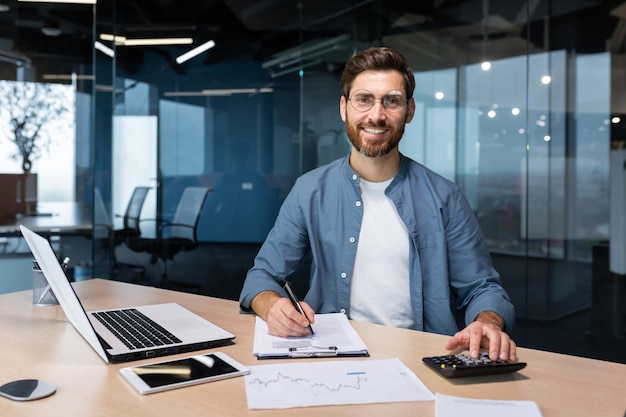 Portrait d'un homme d'affaires prospère derrière un homme de travail sur papier en chemise souriant et regardant la caméra