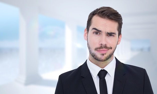 Portrait d'un homme d'affaires sceptique bien habillé contre une salle blanche lumineuse avec des colonnes